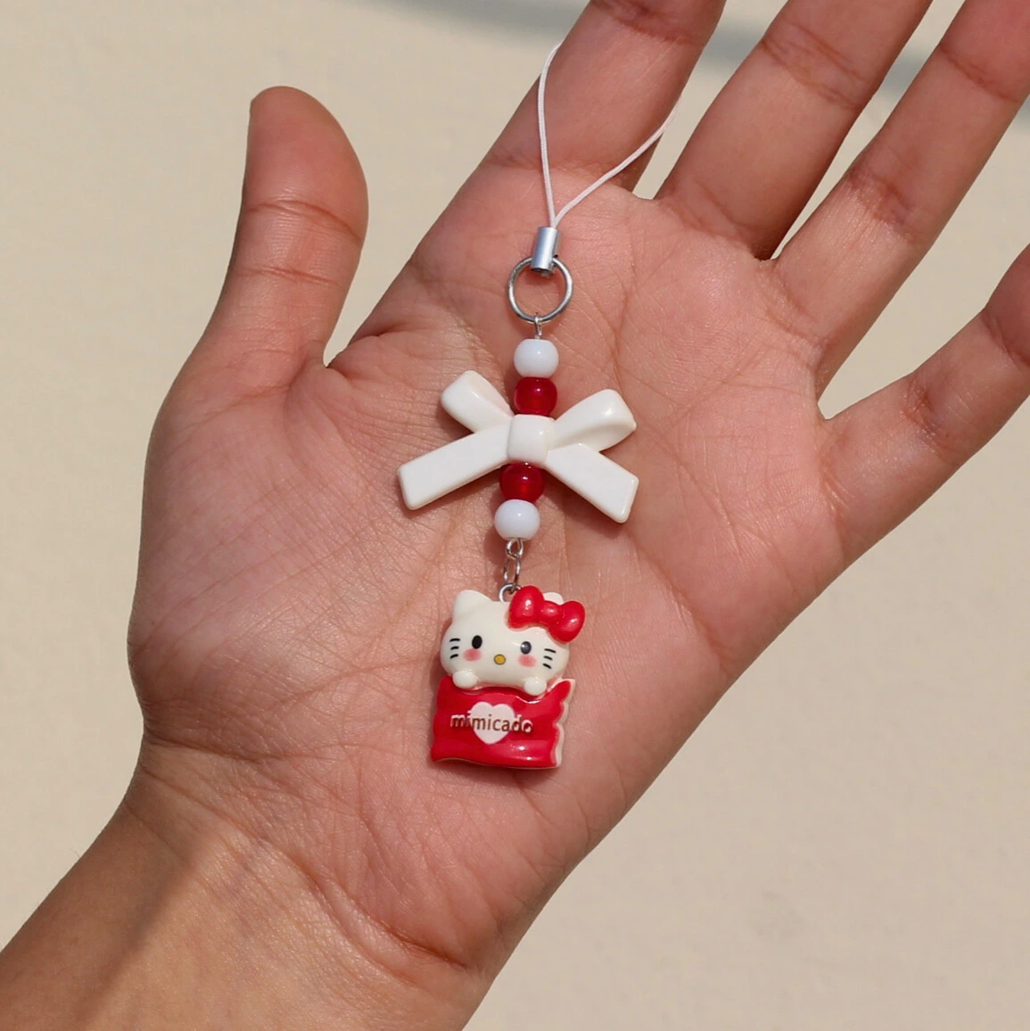 Hello Kitty Cup Cake Phone Charm in the Hand Overview Image